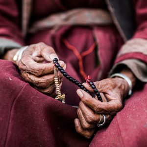 Hands counting red prayer beads in Ladakh, India