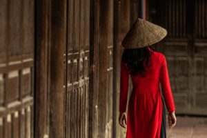Woman in red ao dai moving through an old pagoda in Hoi An