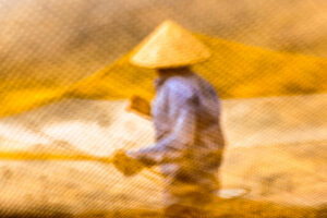 Man seen through yellow fishing net mesh in Hoi An