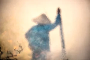 Impressionist photograph of a farmer standing in a rice field in Hoi An, captured through flames by Rehahn.